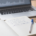 A calm wooden trading desk with an open notebook, a blue Bic pen and a defocused candlestick chart on a laptop, beside two yellow sticky notes reading WAIT and CLICK.