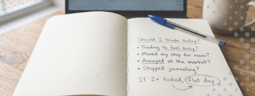 A flat-bound notebook open on a wooden desk with a handwritten pre-session check headed 'Should I trade today?', four warning-sign questions, and 'flat day' circled, a blue Bic pen on the page.