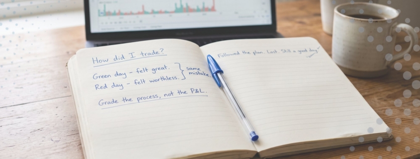 A trading journal open on a desk with a handwritten note reading grade the process, not the P&L