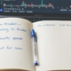 A trading journal reading I'm learning to trade beside a laptop chart on a wooden desk