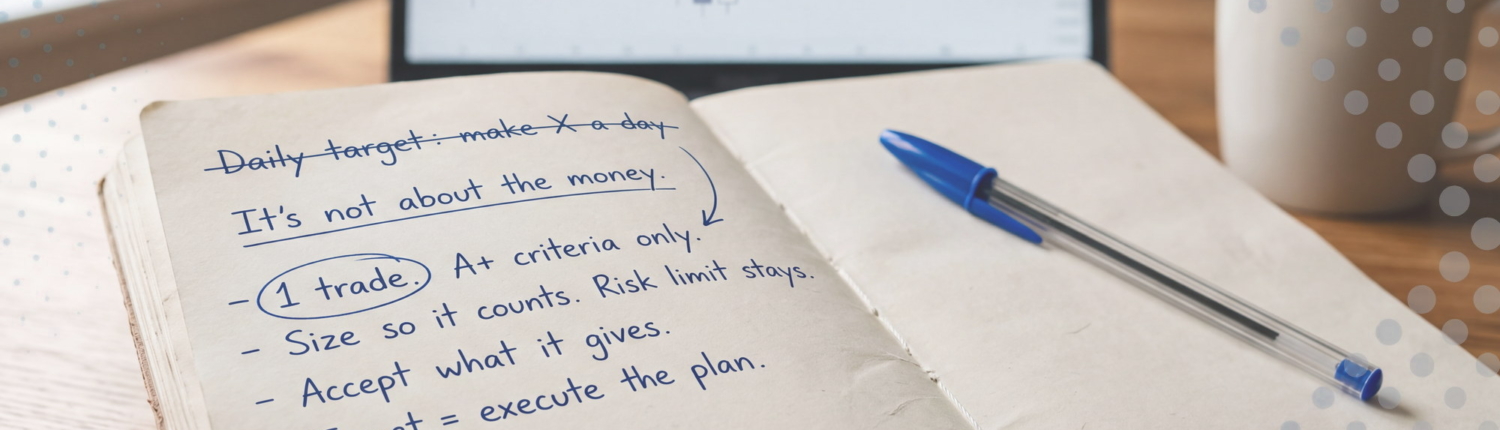Open notebook on a wooden desk with handwritten notes in blue ink: "Daily target: make X a day" crossed out, then "It's not about the money" and a list starting with a circled "1 trade".
